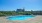 resort style pool with seating and a view of a large building and trees